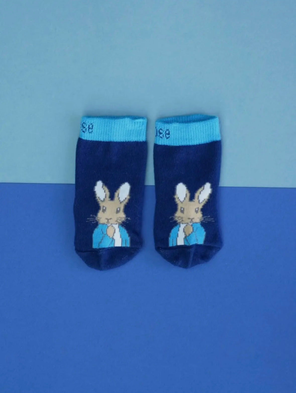 Pair of blue socks with a Peter Rabbit on a blue background