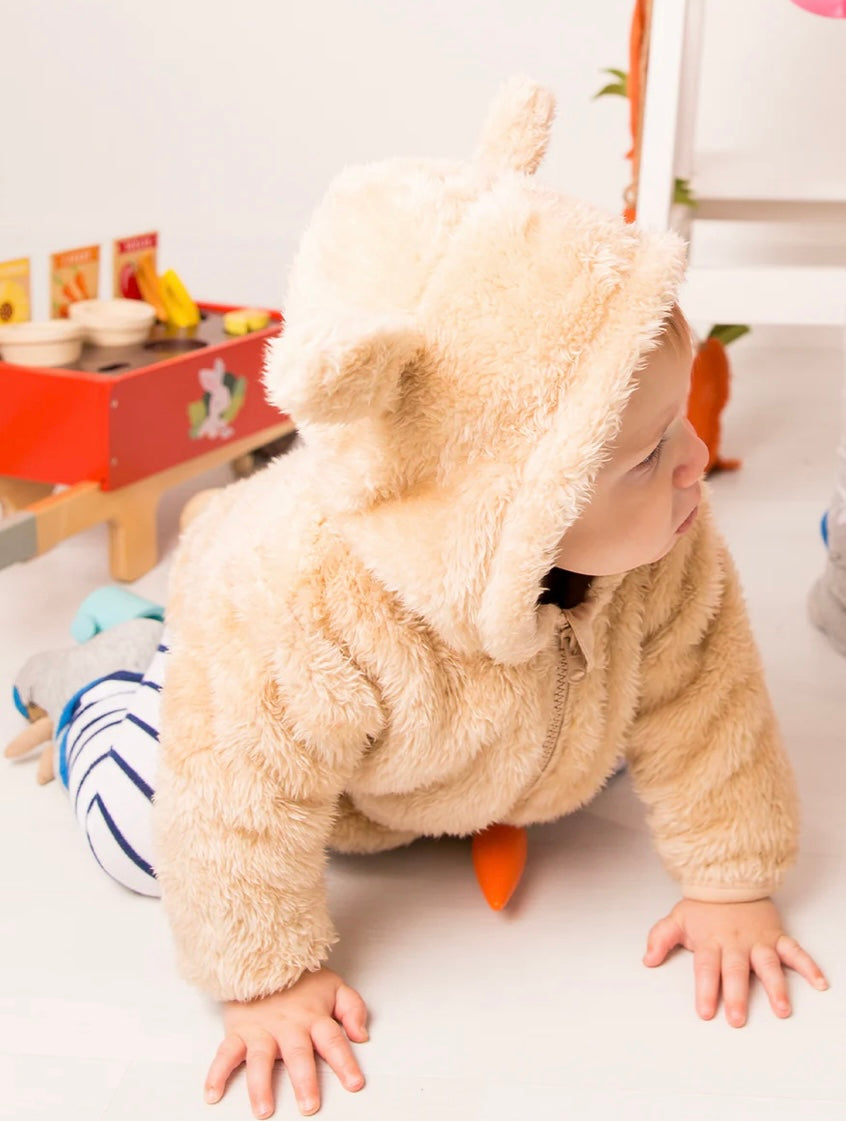 Child in a fluffy beige Peter Rabbit Hoodie with a hood, crawling on a light-colored floor.