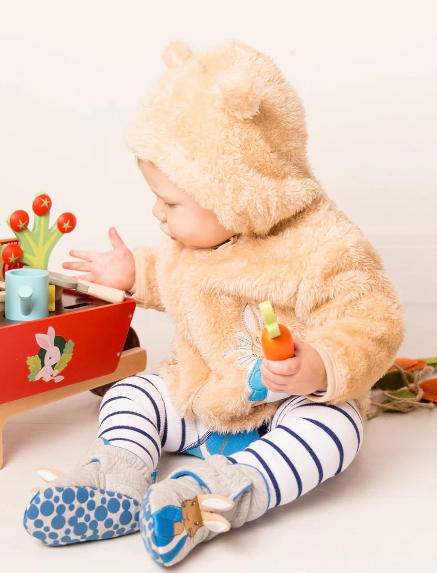 Child in a Peter Rabbit Hoodie playing with toys on a white floor.