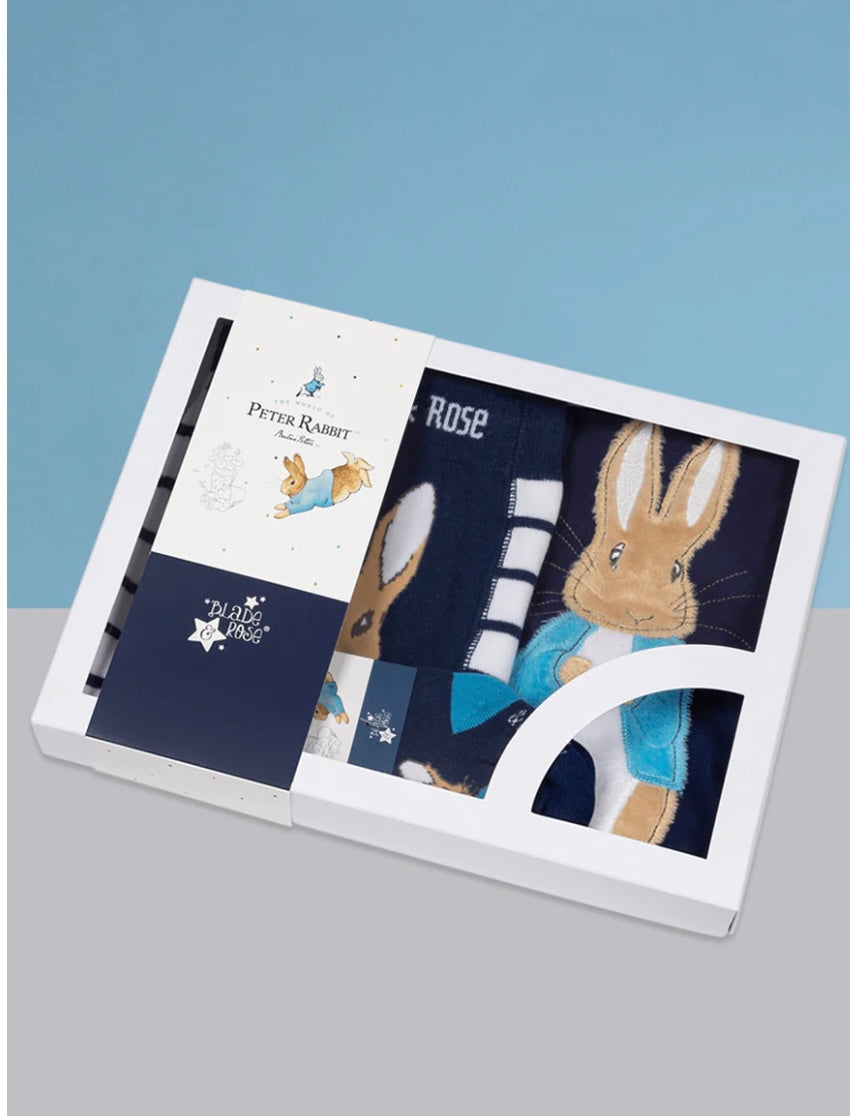 Children's clothing set with Peter Rabbit design in a box on a gray surface.